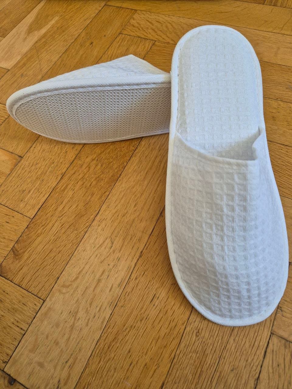 Waffle closed-toe hotel slippers near rattan basket